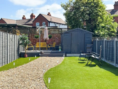 Spacious private garden with lawn, gravel walkway and outdoor seating area.