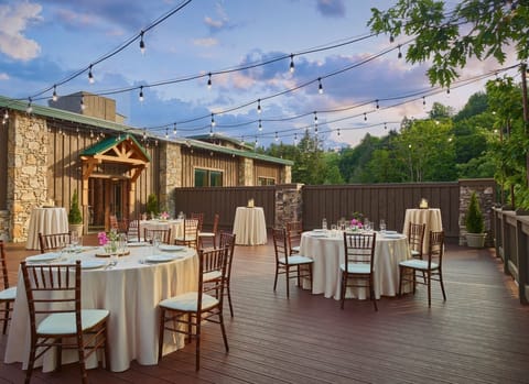 Charming outdoor dining space adorned with string lights and surrounded by lush greenery, perfect for an intimate gathering under the stars.