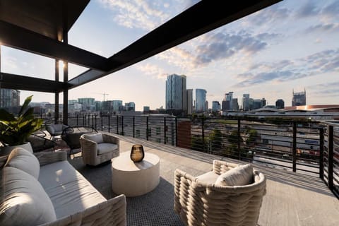 Stylish and inviting balcony with modern furnishings, lush greenery, and stunning city skyline views.