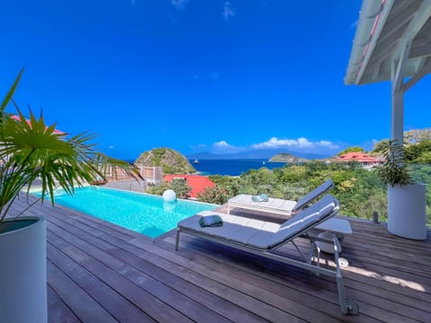 A stylish terrace with an infinity pool and breathtaking views of the ocean and lush hills.