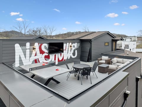 Patio: Experience panoramic views from the rooftop deck featuring a ping pong table, sectional lounge, and outdoor TV under the open sky.