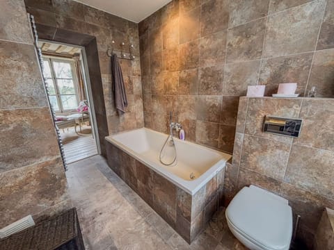 Enjoy the en-suite bathroom adjoining the master suite, featuring a walk-in shower, bathtub, vanity unit, and toilet.