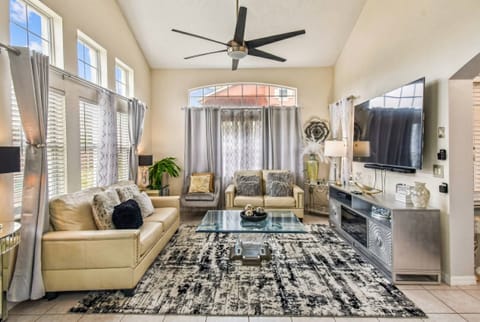 Enjoy the warm natural light pouring in through large windows in this stylish living room, complete with a sleek glass coffee table and a striking area rug. The contemporary seating beckons you to relax in this inviting space.