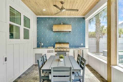 Screened in porch with built-in gas grill, sink, fridge, dining table, lounge seating, and a 4K Smart TV