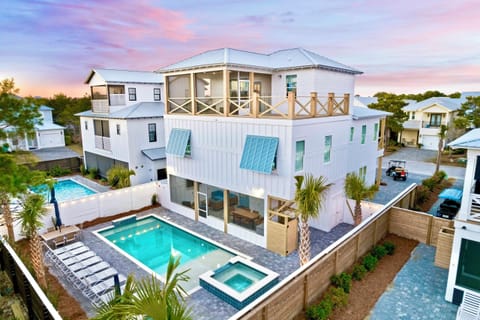 Funky Flamingo – sleeps 28! Steps from private gated beach access with a FREE golf cart. Relax in your backyard oasis with a HEATED pool, hot tub, hammocks, lounge chairs, outdoor dining, and a screened-in kitchen + lounge—perfect for groups + families.