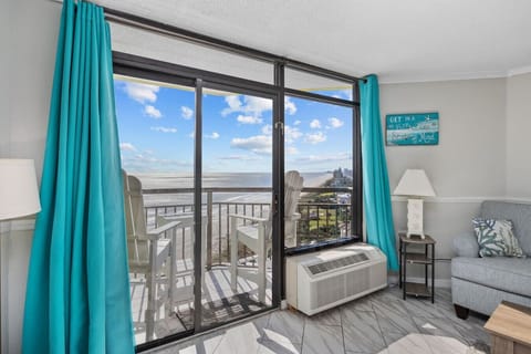 Luxurious penthouse suite with a spacious king bed and floor-to-ceiling windows showcasing sweeping ocean views.