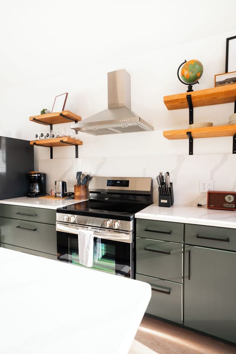 Kitchen at Hemingway — dark cabinetry, full-size appliances, open shelving, everything needed for a real meal
