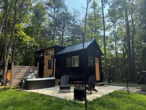 Hughes exterior daytime — modern black exterior, surrounded by mature trees, part of the tiny home collection