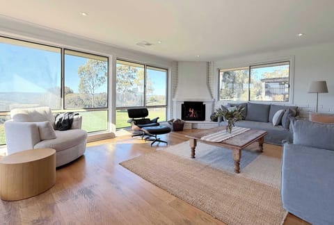 Spacious living room with fire place and floor to ceiling windows to capture the views across the valley.