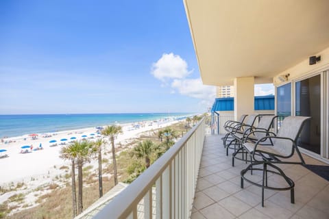 Relax on your private balcony with stunning ocean views, watching beachgoers enjoy the pristine white sand below.