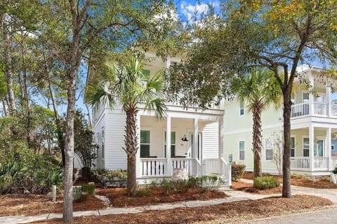  Charming white cottage framed by palm trees and a welcoming front porch.  