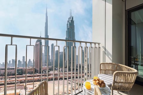 This charming balcony offers stunning views of the Burj Khalifa, Dubai Mall, the courtyard, and pool, featuring two seats and a marble table—perfect for enjoying your morning coffee outdoors.