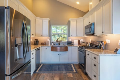 Fully equipped kitchen with a refrigerator, gas stove, dish washer and cookware.