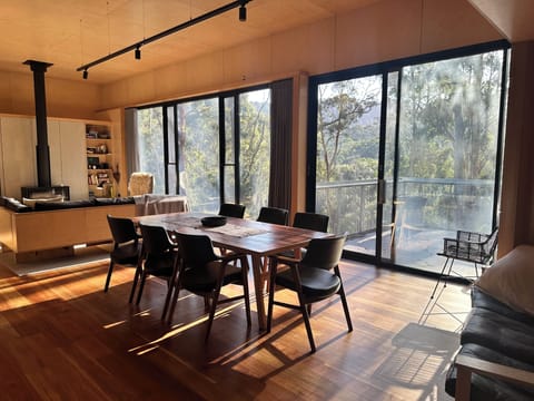 Huge living and dining space with balcony and forest views.