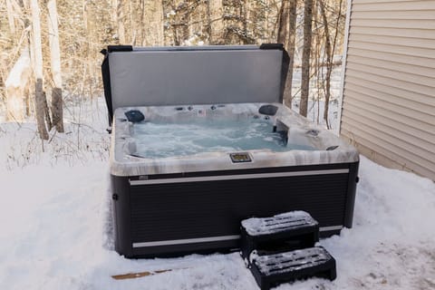 Just steps from the screen porch, immerse yourself in the warmth of the large hot tub, surrounded by the peaceful trees of our wooded lot—pure relaxation in any season.
