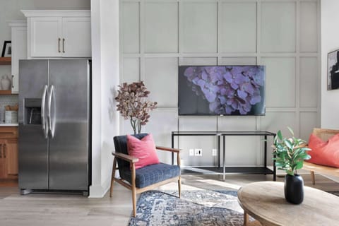 Stylish living room featuring a wall-mounted smart TV, a sleek leather couch, a modern coffee table, and three elegant accent chairs for a cozy and inviting ambiance.