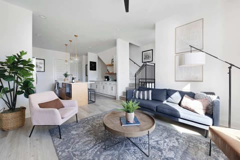 Inviting living room with a wall-mounted smart TV, a sleek leather couch, a stylish coffee table, and three accent chairs, creating a cozy and comfortable space.