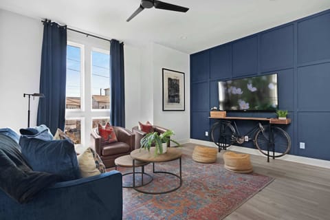 Inviting living room with a wall-mounted smart TV, a pull-out sofa bed, a stylish coffee table, and comfortable accent chairs, perfect for relaxing and entertaining.