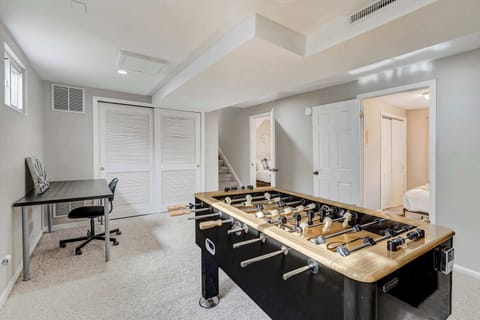 This versatile game and workspace features a foosball table, a wall-mounted TV, and a dedicated desk areaโperfect for both entertainment and productivity. A great space to unwind or catch up on work.