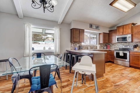 The dining area is designed for gathering, featuring a modern glass-top table, stylish seating, and a high chair for little ones. Natural light pours in, creating a warm and inviting space for meals and conversation.