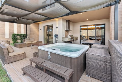 Step outside to enjoy a cozy outdoor space with a modern hot tub and comfortable woven seating. The warm wood tones and soft neutral colors create a relaxed atmosphere, ideal for unwinding after a day of adventure.