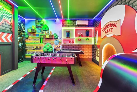 Welcome to our vibrant game room, where colorful neon lights and playful decor create a lively atmosphere. Enjoy friendly competitions at the foosball table and bond with family for a joyful experience.