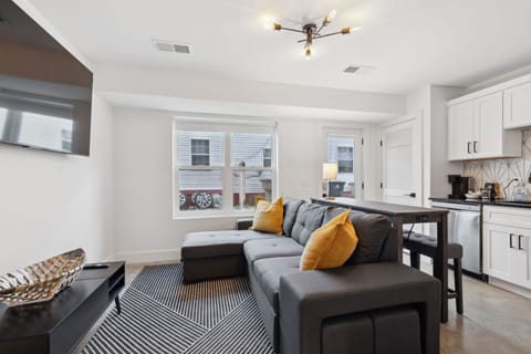 Living Room: Spacious living area with a wall-mounted TV, modern light fixtures, and a large sectional sofa for family gatherings.