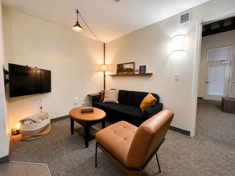 Relax in the open-concept living area featuring soaring industrial ceilings, plush seating, and a versatile dining table/workspace