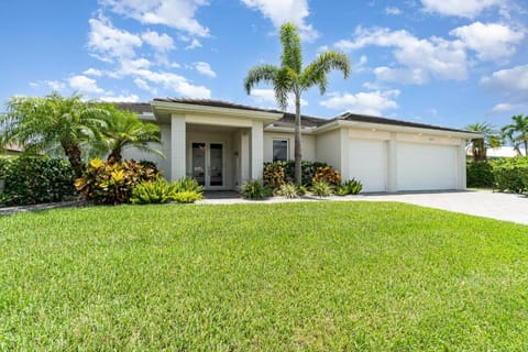 Welcoming single-story home with a spacious driveway and lush landscaping, perfect for a relaxing getaway.