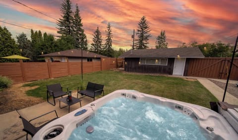 Relax in the private hot tub surrounded by a spacious backyard with yard games and cozy outdoor seating, perfect for family fun in the heart of the neighborhood.