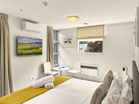 Bright bedroom with king bed, seating, air con/heat pump, TV, kitchenette and ensuite access