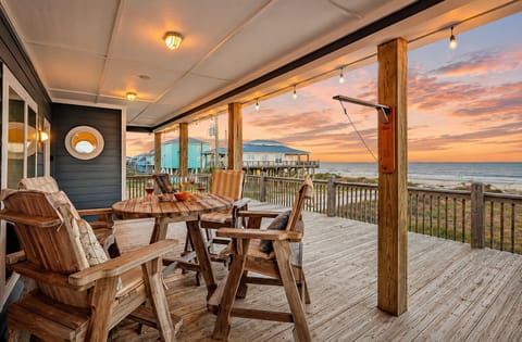 Spacious beachfront deck with outdoor dining, rocking chairs, and panoramic Gulf views at Bolivar Peninsula, TX. Perfect for relaxing coastal vacations and sunset gatherings.