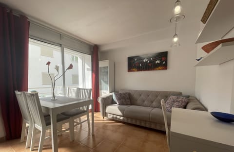 Bright living-dining room with sofa, dining table for four and access to the terrace, ideal for relaxing or enjoying family meals.
