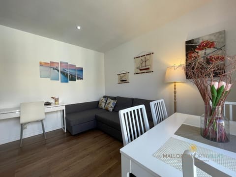 Bright and cozy apartment featuring a nautical-inspired decor, a gray chaise lounge sofa, a white dining table, and a small desk. Functional and inviting, perfect for a comfortable stay in Mallorca.