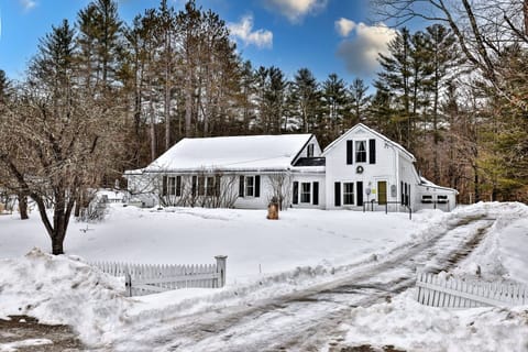 Historic, rustic farmhouse in the beautiful Vermont winter, covered in snow and surrounded by birch trees and a snow field.