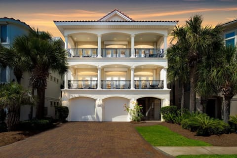 Elegant three-story vacation home with spacious balconies and tropical palm landscaping welcomes guests at arrival.