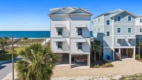 Modern beachfront properties with coastal architecture and tropical landscaping, situated on a sandy shore with direct ocean access and neighboring vacation homes.