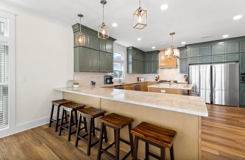 Your gourmet kitchen features sleek green cabinetry, spacious quartz counters, and stylish pendant lighting perfect for cooking memorable meals together.