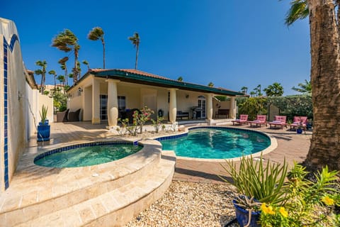 A serene outdoor space with a pool, jacuzzi, and tropical landscaping.