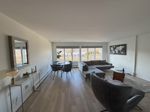 Open living room with modern, comfortable furniture and motorized blinds.