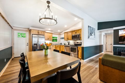Open concept kitchen and dining area complete with fridge, dishwasher, microwave, stove, and large dining table big enough for the whole crew.