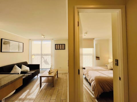 Open living area flowing into the bedroom, filled w/ soft natural light.