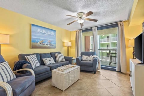 Designed for comfort, this stylish living area has a blue sofa set with nautical-themed pillows, a charming white coffee table, and vibrant beach-inspired artwork. The warm lighting and balcony access make it the best spot to unwind.