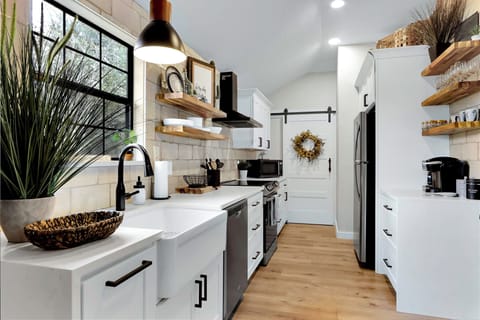 Looking down the length of the kitchen showing the farm house sink, dishwasher, microwave and refrigerator.