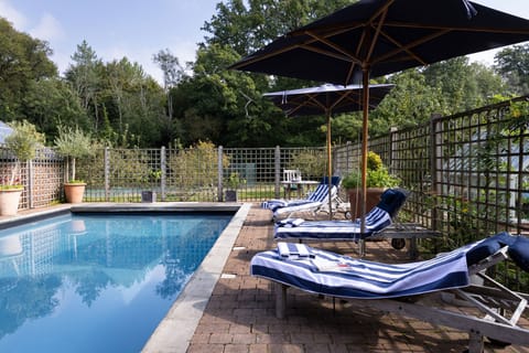 The swimming pool with the tennis court beyond