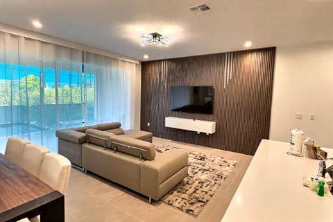 Bright and airy, this living area features a contemporary sofa set against a textured accent wall, perfect for relaxation. Large windows drench the space in natural light, enhancing the stylish decor and inviting ambiance.