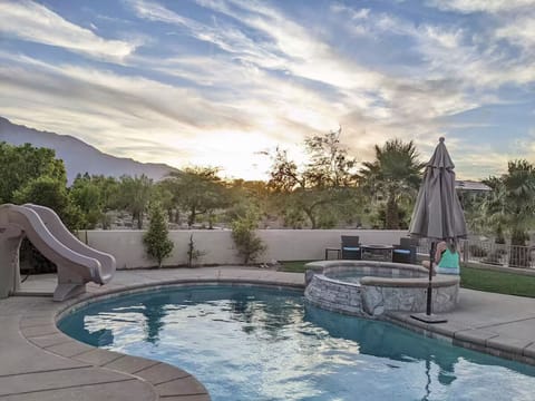 Dive into desert paradise—sparkling pool, slide & spa beneath sunset mountains