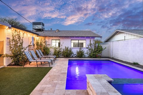 Unwind in your private backyard oasis, where glowing pool lights, cozy loungers, and desert sunset skies set the scene for the perfect evening swim.