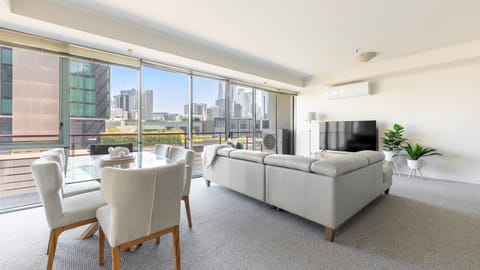 Bask in natural light within a grand living and dining domain, complete with an expansive leather sectional and sweeping urban views.