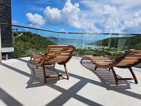 Top-floor balcony featuring sun loungers and unobstructed ocean views.